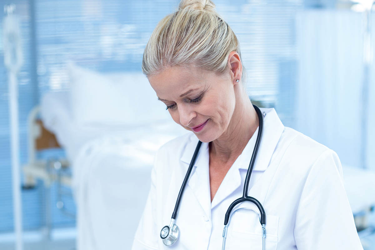 Smiling doctor writing on clipboard